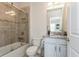 Bathroom featuring white vanity, granite countertop, tile floors, and a tub shower with glass doors at 4973 Antiquity Way, Sarasota, FL 34240