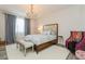Bedroom with natural light, chandelier, light gray walls, white rug, and a stylish wood-framed bed at 4973 Antiquity Way, Sarasota, FL 34240