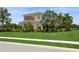 Stunning two-story home featuring lush landscaping, vibrant flowers, and a well-manicured lawn at 4973 Antiquity Way, Sarasota, FL 34240