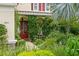 Charming front entrance adorned with climbing vines and a striking red door, surrounded by lush greenery at 4973 Antiquity Way, Sarasota, FL 34240