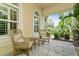 Inviting covered front porch with wicker seating and a small table, perfect for relaxing outdoors at 4973 Antiquity Way, Sarasota, FL 34240