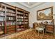Spacious home office showcasing custom shelving, a traditional desk, and a patterned area rug at 4973 Antiquity Way, Sarasota, FL 34240