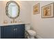 Stylish powder room with blue vanity, gold fixtures, and decorative mirror and artwork at 4973 Antiquity Way, Sarasota, FL 34240
