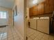 Bright laundry room with tile flooring, washer, dryer, and wooden cabinets at 5004 Grainary Ave, Tampa, FL 33624