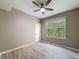 Bright bedroom featuring wood-look floors, a ceiling fan, and a window with views of lush greenery at 5125 Palm Springs Blvd # 3108, Tampa, FL 33647