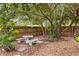 Secluded backyard retreat featuring a stone table with benches, nestled amongst lush greenery and mature trees at 549 39Th Ne Ave, St Petersburg, FL 33703