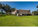 Exterior view of a condo building with a green lawn, parking, and mature trees at 6190 80Th N St # 310, St Petersburg, FL 33709