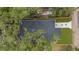 Aerial view of a home with a dark roof, surrounded by mature trees and a fenced-in yard at 7509 E 26Th Ave, Tampa, FL 33619