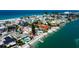 Aerial view of colorful neighborhood with beachfront homes, private beaches, boat docks, and swimming pools on a sunny day at 7777 Bayshore Dr, Treasure Island, FL 33706