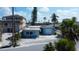 View of charming light blue home with white trim, a separate garage, and tropical landscaping on a sunny day at 7777 Bayshore Dr, Treasure Island, FL 33706
