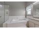 Bright bathroom featuring a tiled tub, separate glass shower, and granite vanity with window light at 8441 Danbury Ln, Hudson, FL 34667