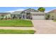 Charming single-story home with a well-manicured lawn, brick driveway, and attached two-car garage at 8441 Danbury Ln, Hudson, FL 34667