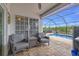 Screened in patio area with two chairs and a table overlooking the in ground pool at 8441 Danbury Ln, Hudson, FL 34667