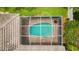 Aerial view of a screened in pool with brick patio and roof, surrounded by lush greenery at 1051 Glynwood Pl, Dunedin, FL 34698
