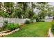 Private backyard with a well-maintained lawn, mature trees, and a white picket fence at 1051 Glynwood Pl, Dunedin, FL 34698