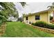Well-maintained backyard featuring green lawn, lush landscaping, and a screen enclosure at 1051 Glynwood Pl, Dunedin, FL 34698