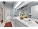 Bright bathroom featuring double sinks, neutral decor, and a glass door leading to the backyard at 1051 Glynwood Pl, Dunedin, FL 34698