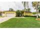 Charming yellow home with a well-manicured lawn and lush tropical landscaping, including mature palm trees at 1051 Glynwood Pl, Dunedin, FL 34698