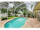 Outdoor pool area with a screened enclosure and a brick-paved deck at 1051 Glynwood Pl, Dunedin, FL 34698