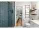 Updated bathroom featuring a glass-enclosed blue tiled shower, modern fixtures, and view into the adjacent bedroom at 111 29Th W St, Bradenton, FL 34205
