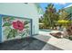Garage with a colorful floral mural, pool, and outdoor seating that adds a unique artistic touch to the property at 111 29Th W St, Bradenton, FL 34205