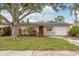 Charming single story home with beautiful landscaping, a red front door, and attached garage at 11320 125Th Ter, Largo, FL 33778