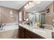 Bathroom featuring dual vanity sinks, granite countertops, a garden tub and a glass shower at 12026 Crestridge Loop, New Port Richey, FL 34655