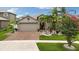 Charming single-Gathering home featuring lush landscaping, palm trees, and a brick driveway leading to a two-car garage at 12026 Crestridge Loop, New Port Richey, FL 34655