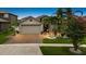 Charming single-Gathering home featuring lush landscaping, palm trees, and a brick driveway leading to a two-car garage at 12026 Crestridge Loop, New Port Richey, FL 34655