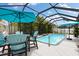 Inviting caged pool and patio area with sunny skies, an outdoor dining area, and garden accents at 12026 Crestridge Loop, New Port Richey, FL 34655