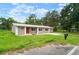 Well-kept single-story home with a metal roof, red front door, green lawn, and rural surroundings at 1217 W Terrace Dr, Plant City, FL 33563