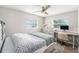 This bedroom features a ceiling fan, two windows, a dresser and a desk with a chair on a rug at 1312 S Evergreen Ave, Clearwater, FL 33756
