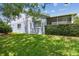 View of the back of the house and lush green yard shaded by a large tree at 13636 Lake Point S Dr, Clearwater, FL 33762
