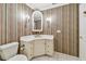 Charming powder room with striped wallpaper, vanity, marble countertop, and decorative lighting at 13636 Lake Point S Dr, Clearwater, FL 33762