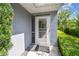 Close-up of the front door with a screen door and a small porch area with decorative landscaping at 13636 Lake Point S Dr, Clearwater, FL 33762