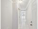 Bright hallway featuring white tile flooring and walls, leading to an open living space with natural light at 13636 Lake Point S Dr, Clearwater, FL 33762