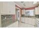 Well-lit kitchen with white cabinetry, mosaic backsplash, and granite countertops at 13636 Lake Point S Dr, Clearwater, FL 33762