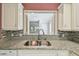 Kitchen sink with granite countertops and mosaic backsplash overlooking the living area at 13636 Lake Point S Dr, Clearwater, FL 33762