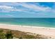 Beautiful beach view showcasing clear blue water, a pristine sandy shore, and lush tropical vegetation at 1380 Gulf Blvd # 805, Clearwater, FL 33767