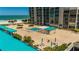 Inviting pool area with lounging chairs, sun shelters, lush landscaping, and building elevation with ocean view at 1380 Gulf Blvd # 805, Clearwater, FL 33767