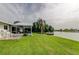 Spacious backyard with mature lawn, a covered patio, and a private boat dock on the water at 1407 Brattleboro Cir, Sun City Center, FL 33573
