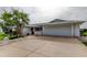 Expansive view of the home's front exterior with a wide driveway, attached garage, and tropical landscaping at 1407 Brattleboro Cir, Sun City Center, FL 33573