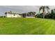 Back exterior with a well-kept lawn, a screened-in patio, and views of the lake at 1407 Brattleboro Cir, Sun City Center, FL 33573