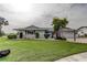 Charming single-story home featuring a lush lawn, manicured bushes, and a driveway leading to an attached garage at 1407 Brattleboro Cir, Sun City Center, FL 33573
