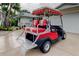 Red and white golf cart featuring a canopy and seating parked on the concrete driveway at 1407 Brattleboro Cir, Sun City Center, FL 33573