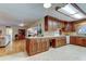 Spacious kitchen featuring wood cabinetry, tile backsplash, countertop seating, and tile floors at 1407 Brattleboro Cir, Sun City Center, FL 33573