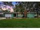 Charming single-story home with a well-manicured lawn, a stone chimney, and lush landscaping at 152 58Th S Ave, St Petersburg, FL 33705