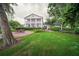 Picturesque view of the backyard featuring a patio, lush green lawn, and a charming two-story home with elegant columns at 15612 Howell Park Ln, Tampa, FL 33625