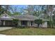 Charming single-story home featuring a lush front yard with mature trees and an attached carport at 17306 Livingston Ave, Lutz, FL 33559