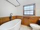 Updated bathroom with modern tub, wooden wainscoting and white tiled floor at 1737 Prince Philip St, Clearwater, FL 33755